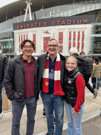 Two students and a professor outside Emirates Stadium.